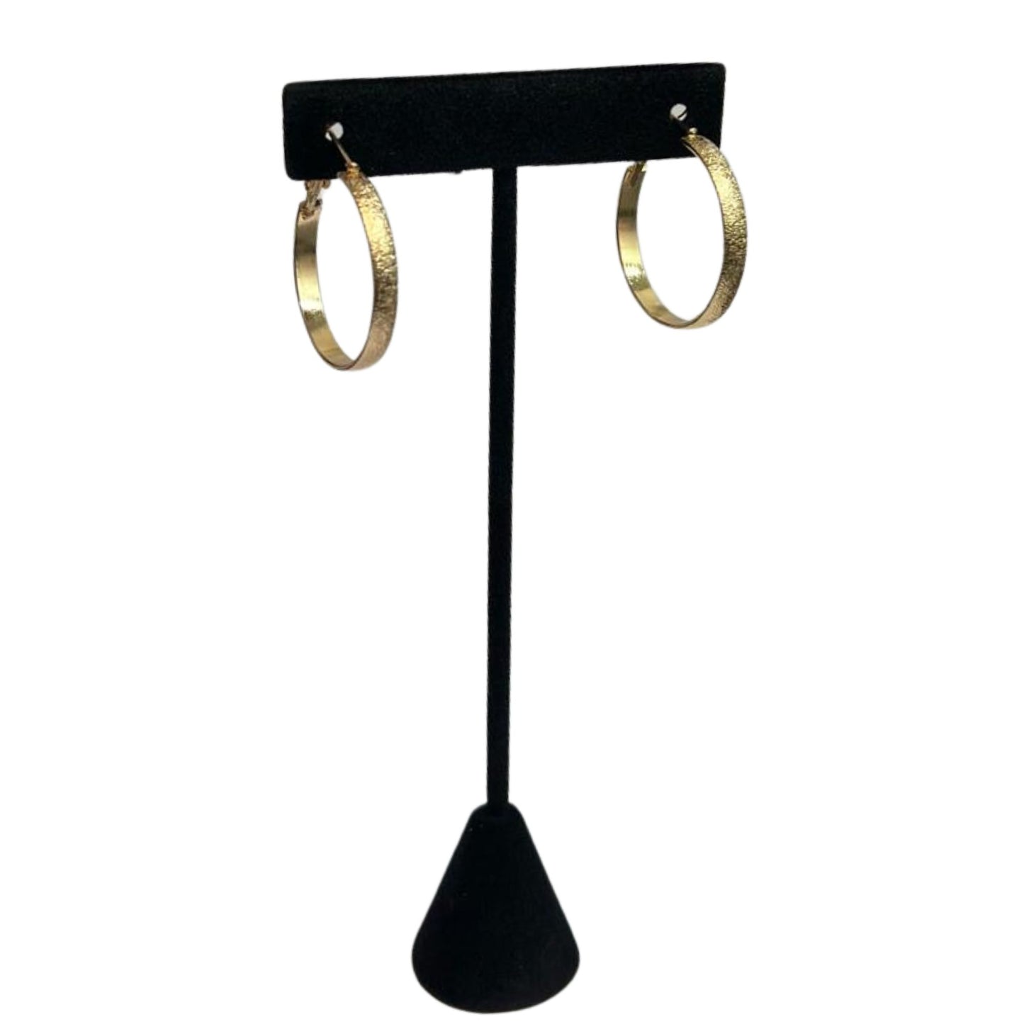 Gold hoop earrings on a black earring stand against a white background