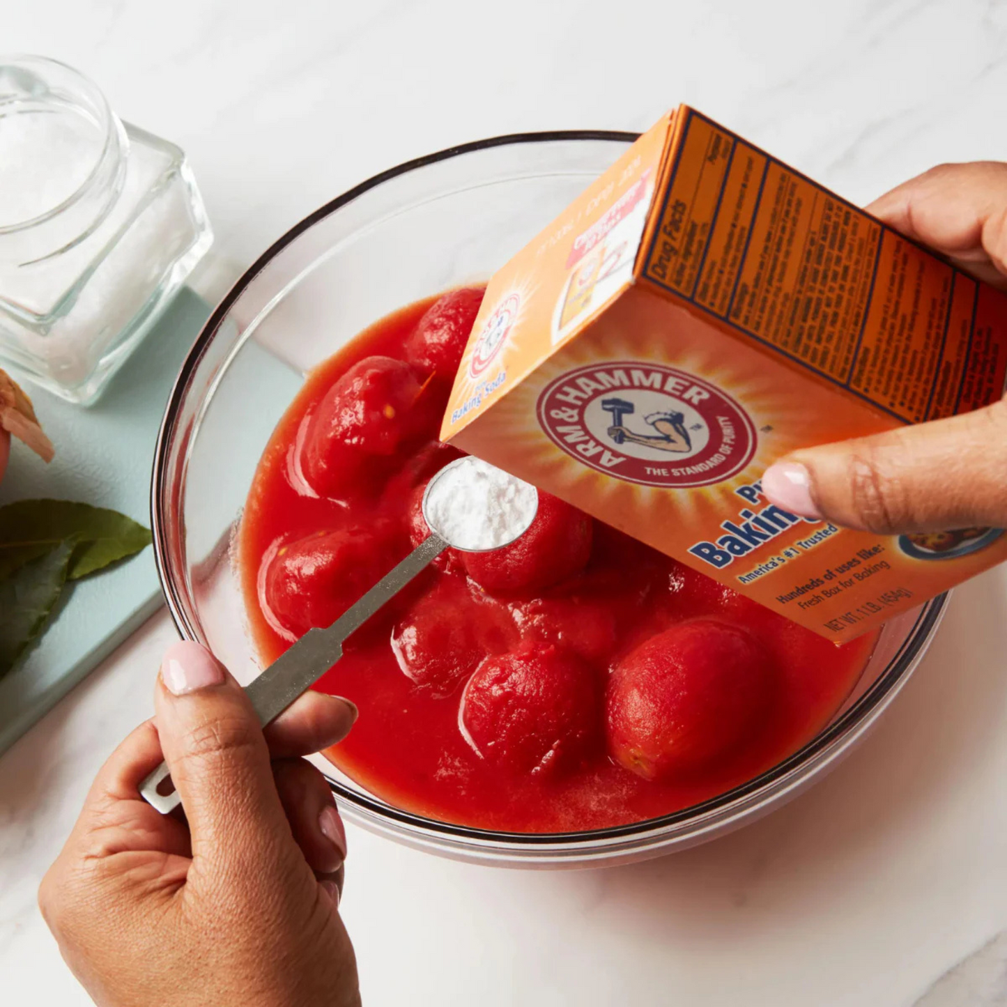 Tomatoes in a bowl with baking soda being added, with Arm & Hammer baking soda box visible.