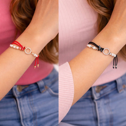 Two different bracelets on a person's wrist with a pink shirt and blue jeans background.