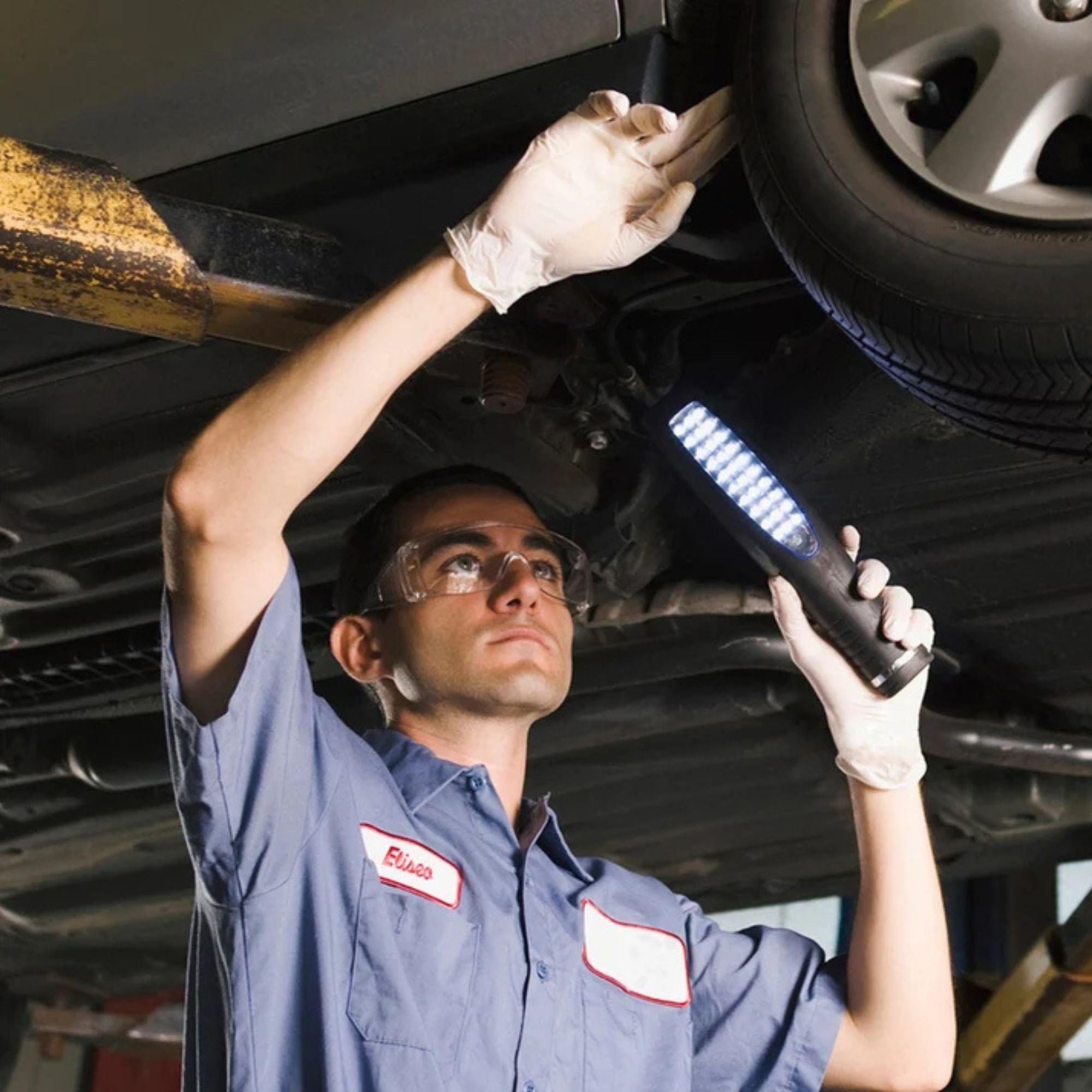 Mechanic working on a car undercarriage with a flashlight