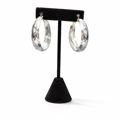 Clear hoop earrings on a black earring stand against a white background