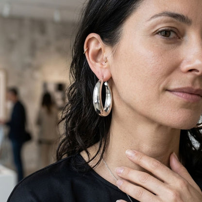 Woman wearing silver hoop earrings with a blurred indoor background