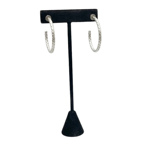 Black T-shaped earring stand with silver hoop earrings on a white background