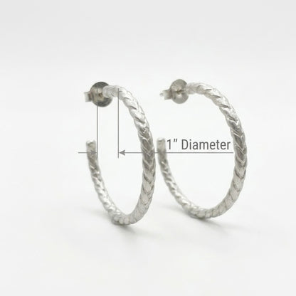 Silver hoop earrings with a 1-inch diameter measurement on a white background