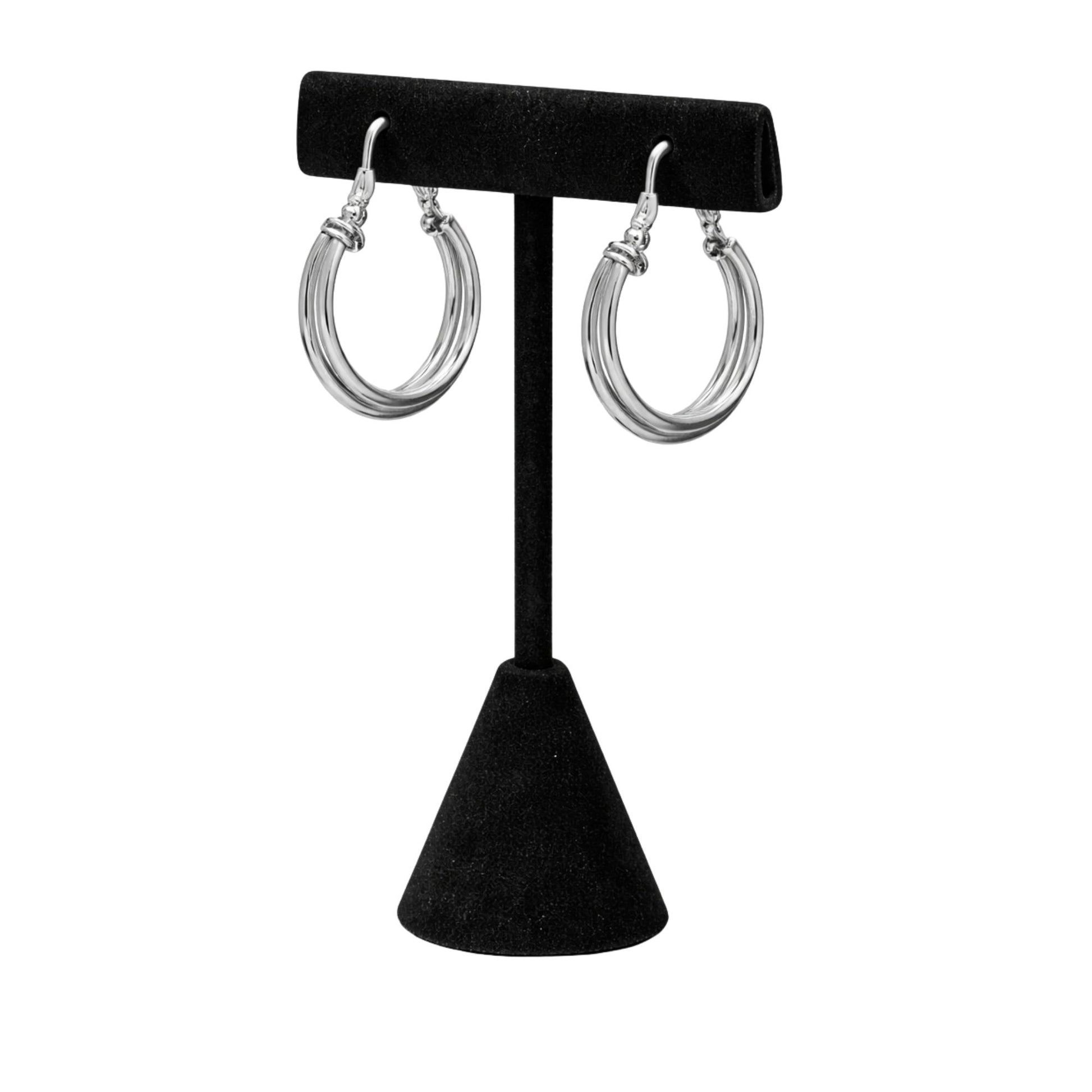 Silver hoop earrings on a black earring stand against a white background
