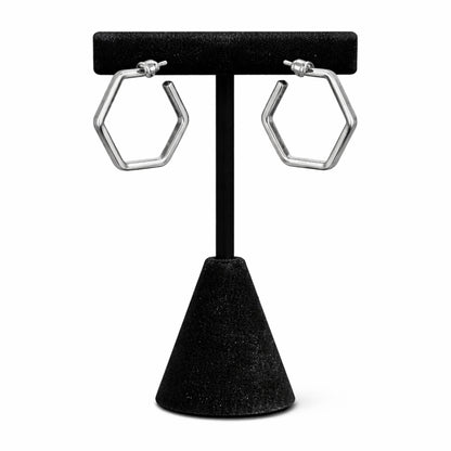 Hexagonal hoop earrings on a black stand against a white background