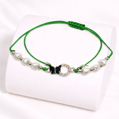 Green bracelet with beads and a butterfly charm on a white background