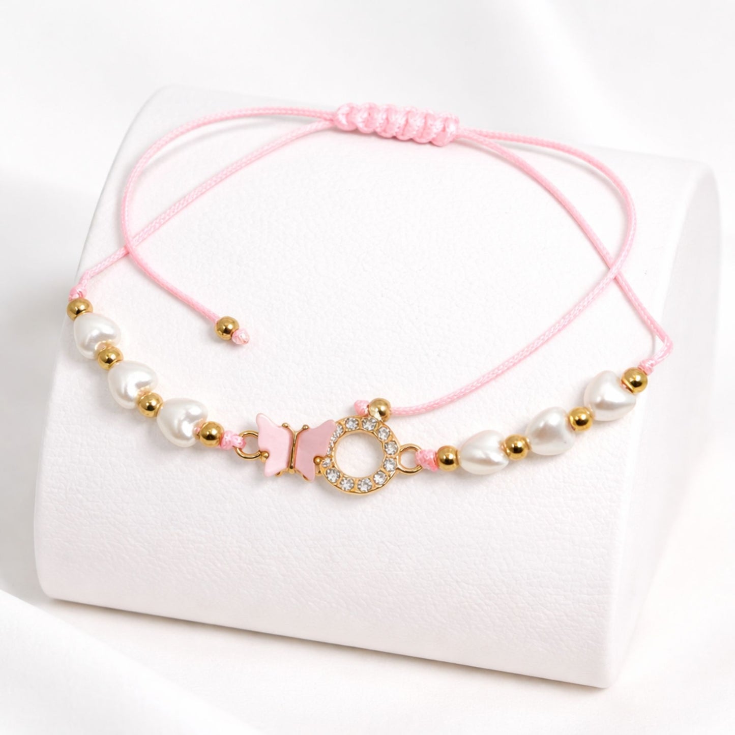 Pink bracelet with pearls and gold beads on a white background