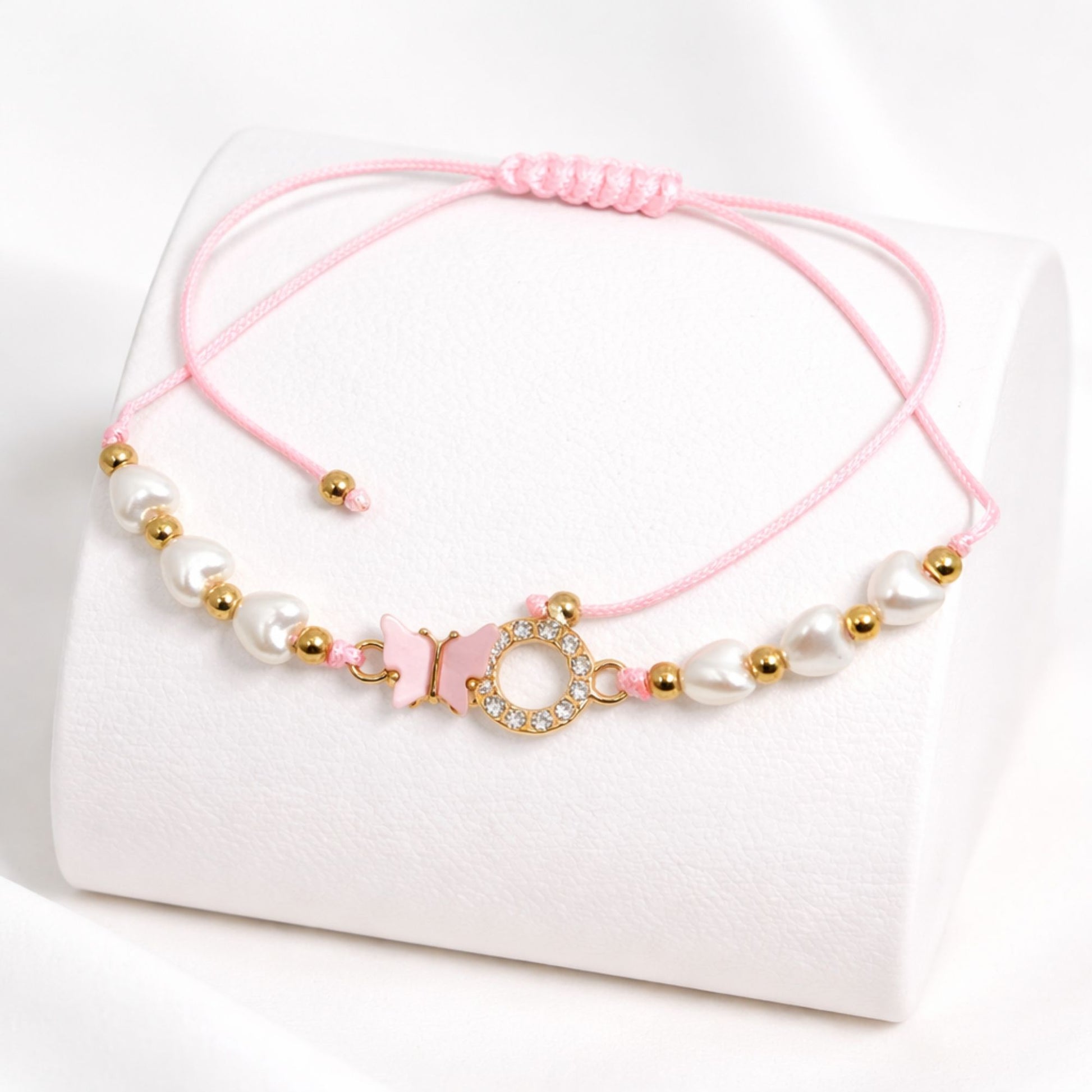 Pink bracelet with pearls and gold beads on a white background