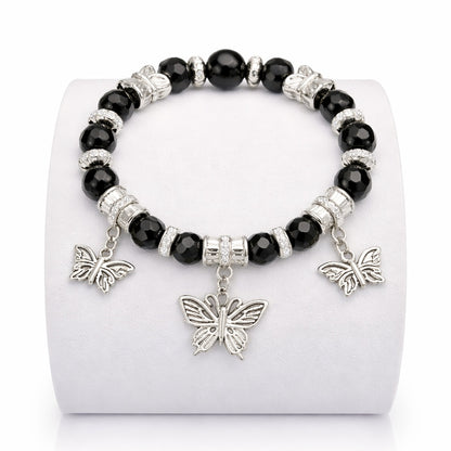 Black beaded bracelet with silver butterfly charms on a white stand