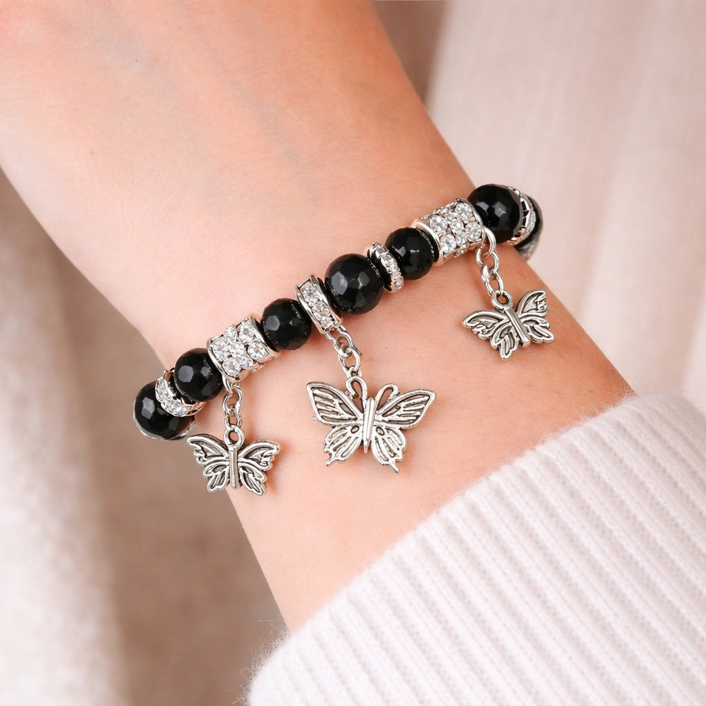 Bracelet with black beads and silver butterfly charms on a wrist.