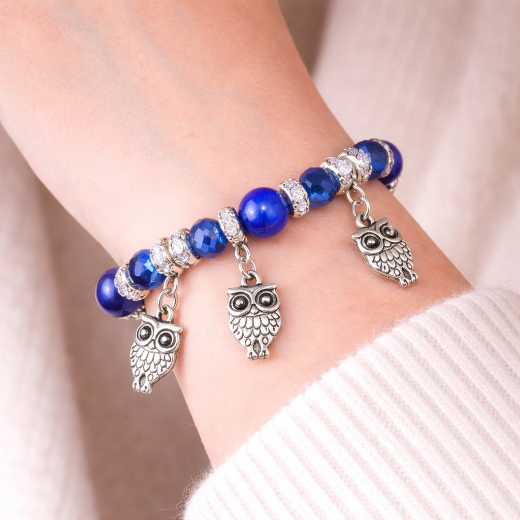 Bracelet with blue beads and owl charms on a wrist