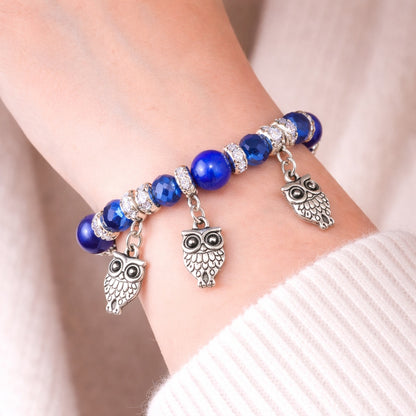 Bracelet with blue beads and owl charms on a wrist