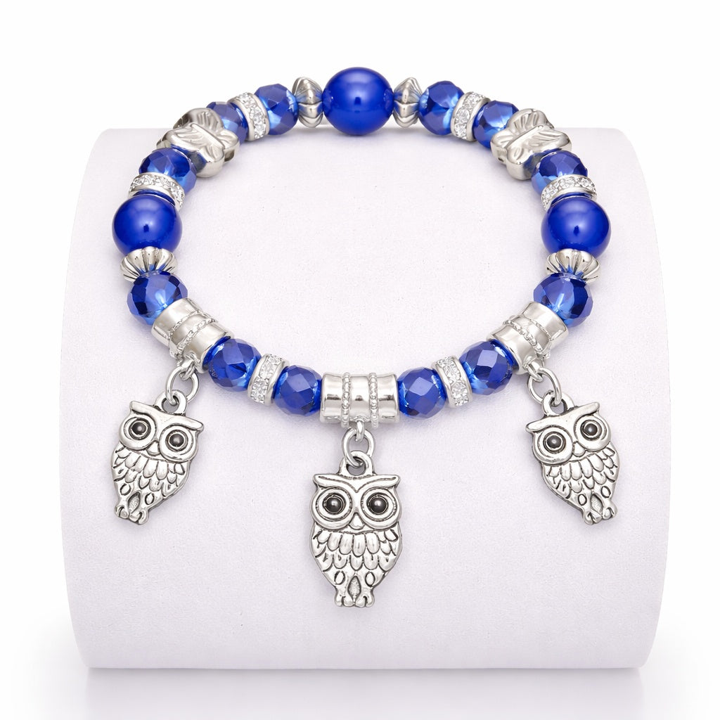 Bracelet with blue beads and owl charms on a white background