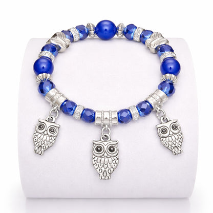 Bracelet with blue beads and owl charms on a white background