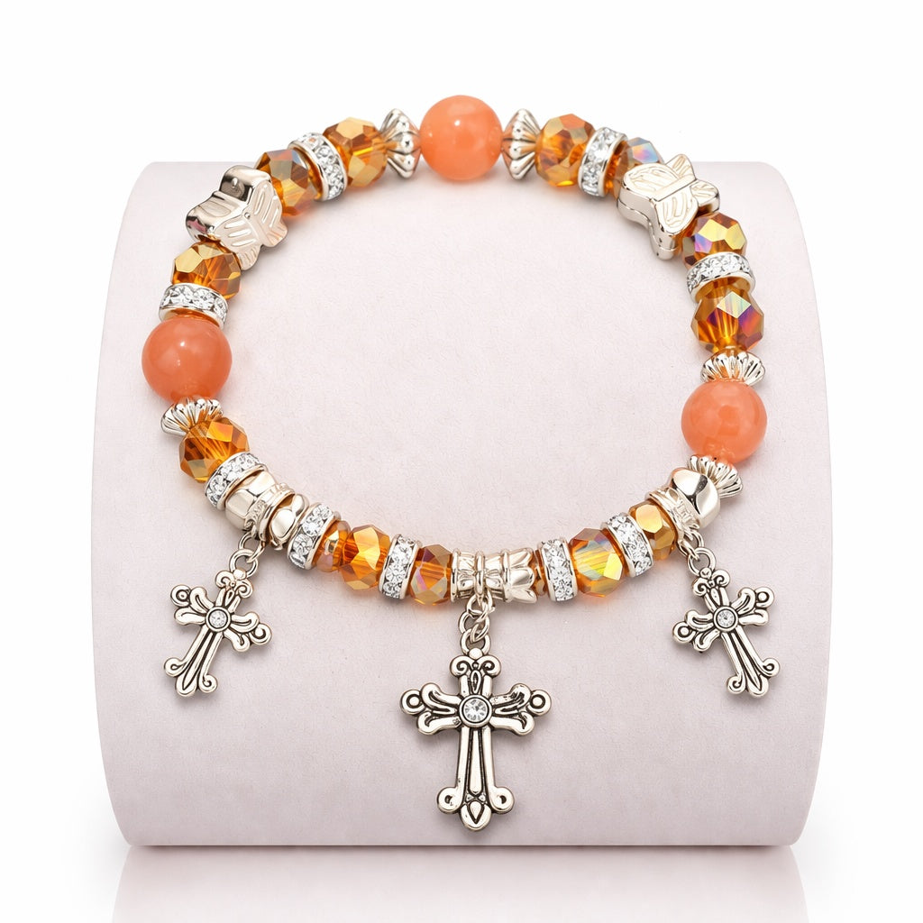 Bracelet with orange beads and silver cross charms on a white background
