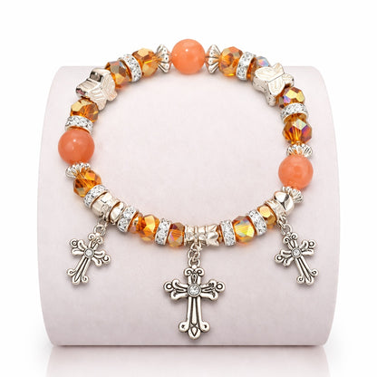Bracelet with orange beads and silver cross charms on a white background