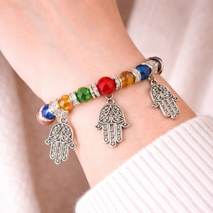 Bracelet with colorful beads and Hamsa hand charms on a wrist.