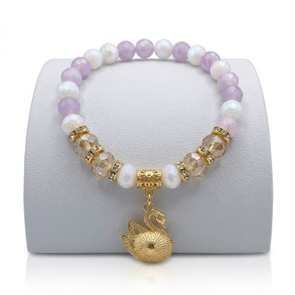 Beaded bracelet with a gold swan charm on a white stand