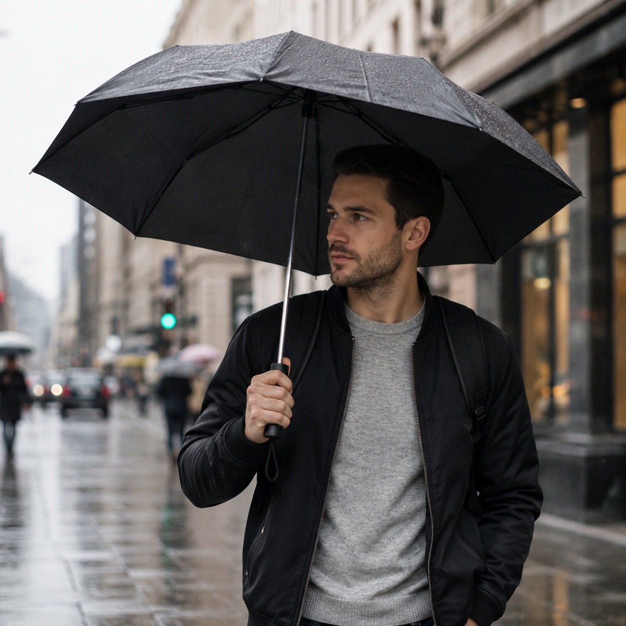 Man holding a black umbrella on a city street