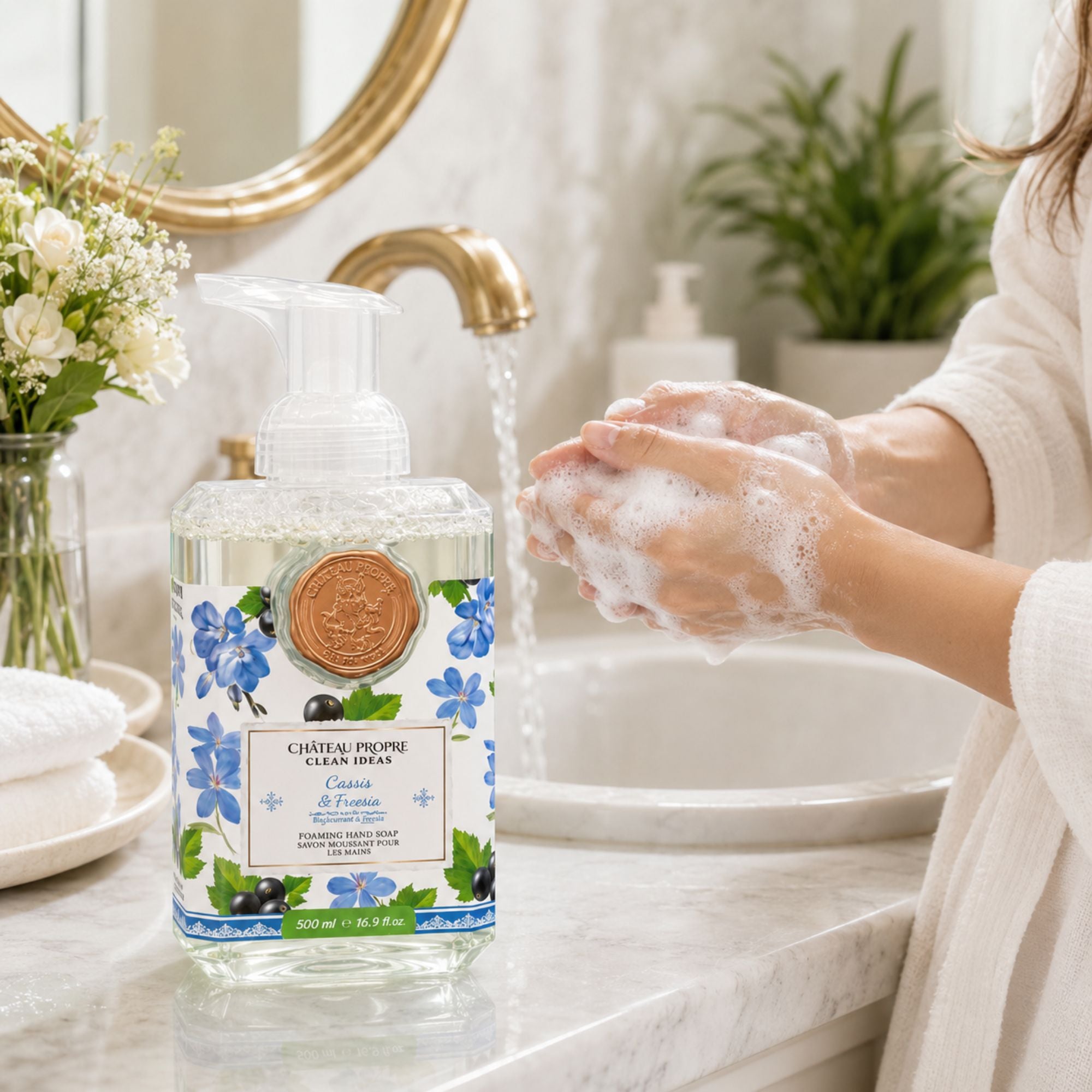 Person washing hands with a foaming hand soap bottle in a bathroom setting.