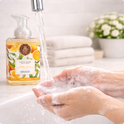 Person washing hands with soap and water, next to a bottle of soap with a citrus design.