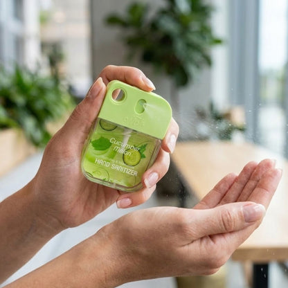 Hand using a small green hand sanitizer bottle with a blurred indoor background