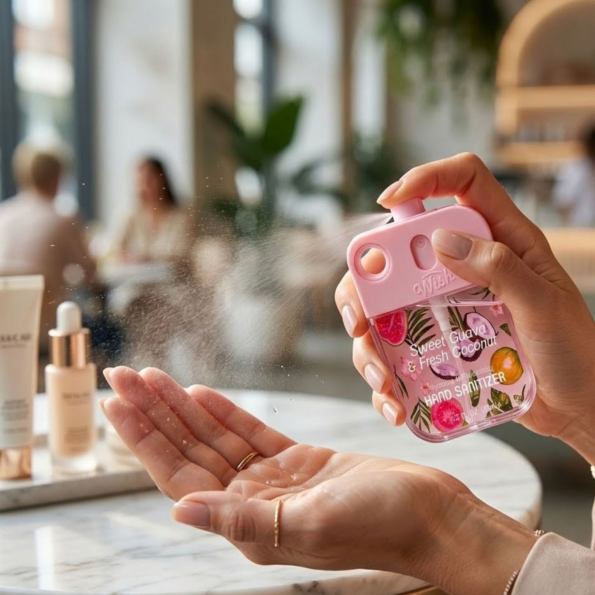 Hand using a pink hand sanitizer with floral design in a blurred indoor setting