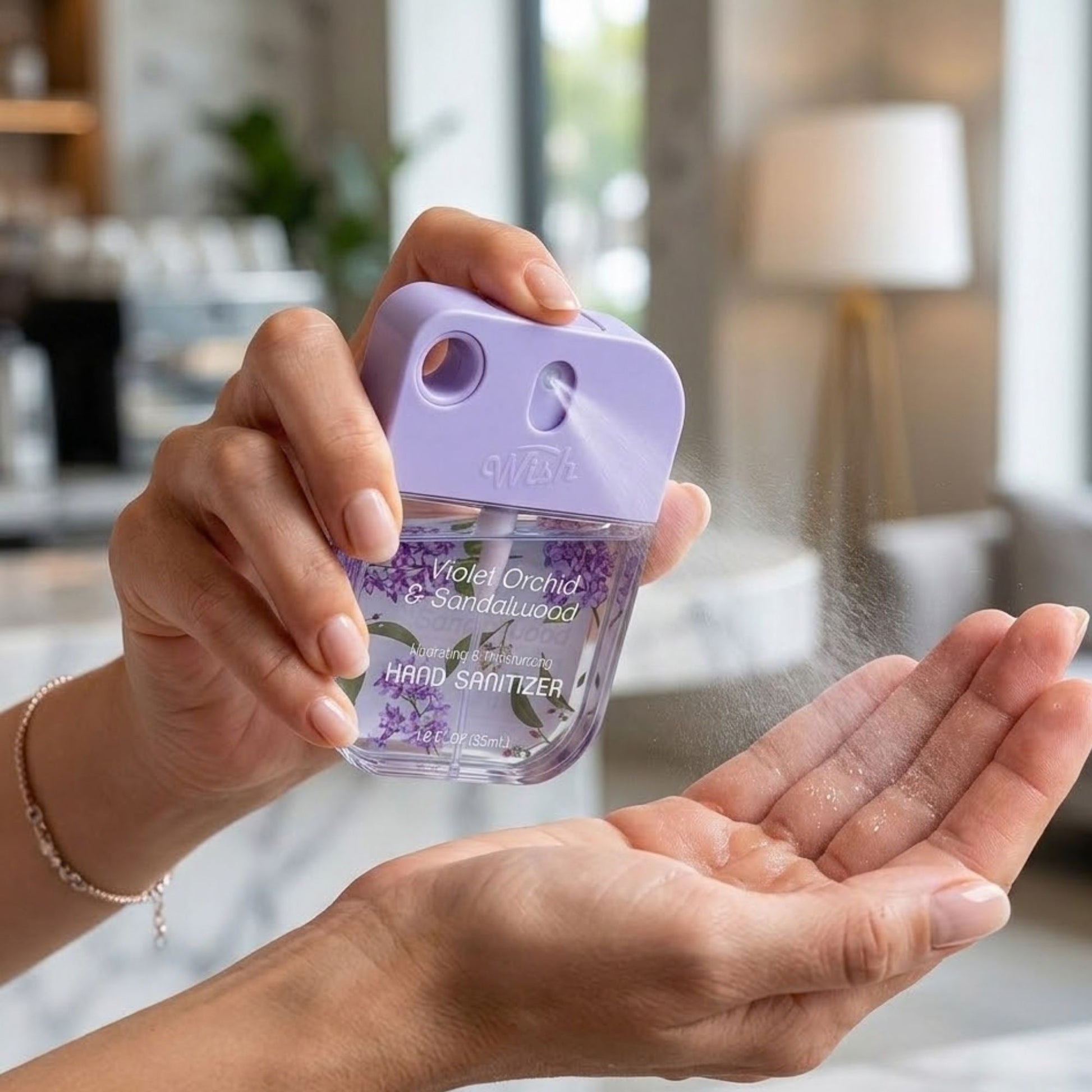 Hand using a purple hand sanitizer with 'Violet Orchid & Sandalwood' scent, held by a person indoors.