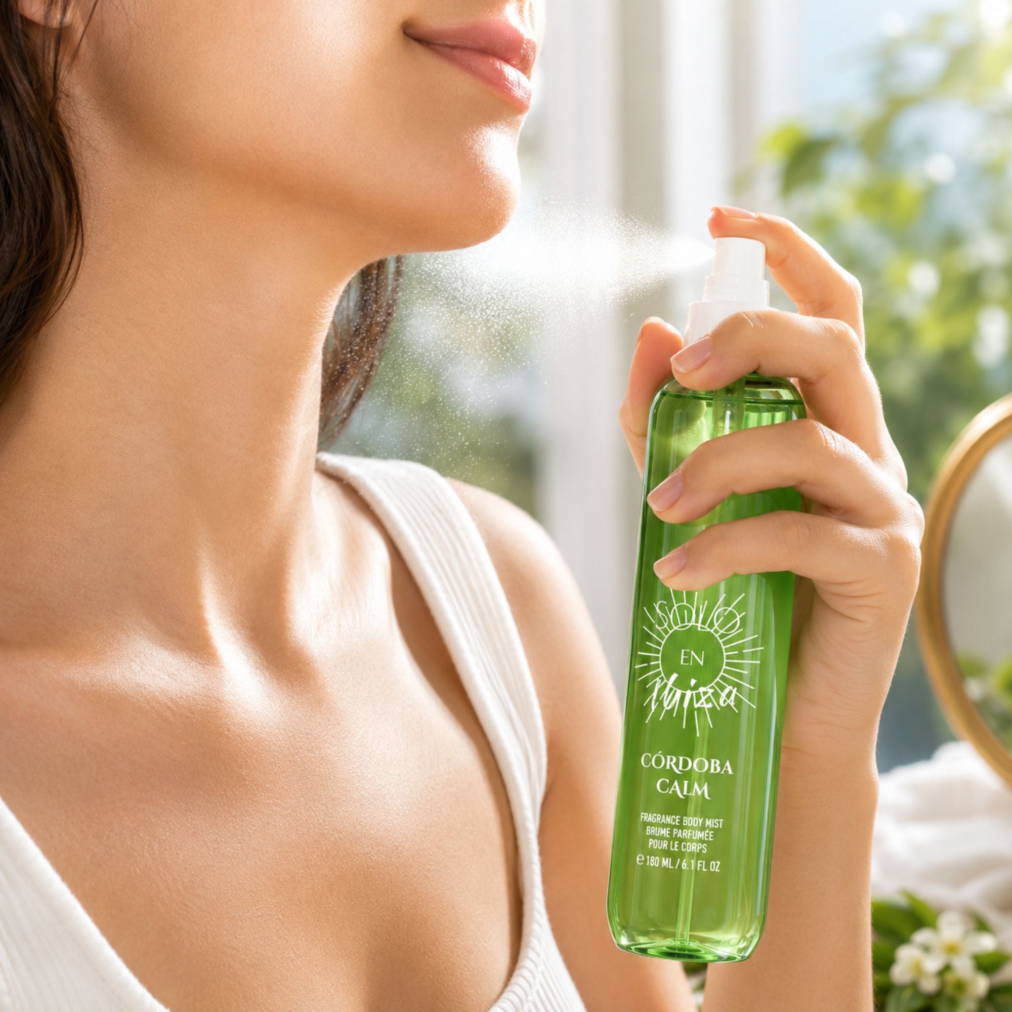 A woman holding a green spray bottle labeled 'IN Vibra CORDOBA CAIM' and spraying it on her neck, with a bright, sunlit background.