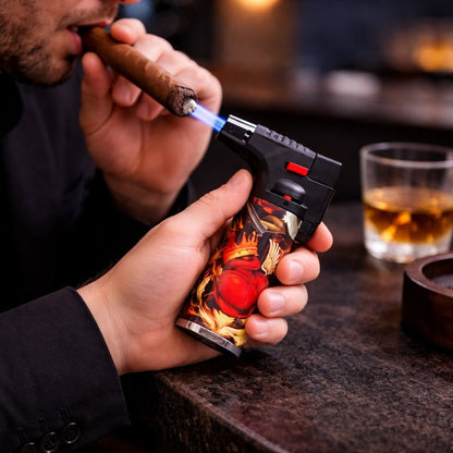 Person lighting a cigar with a decorative lighter, glass of whiskey in the background