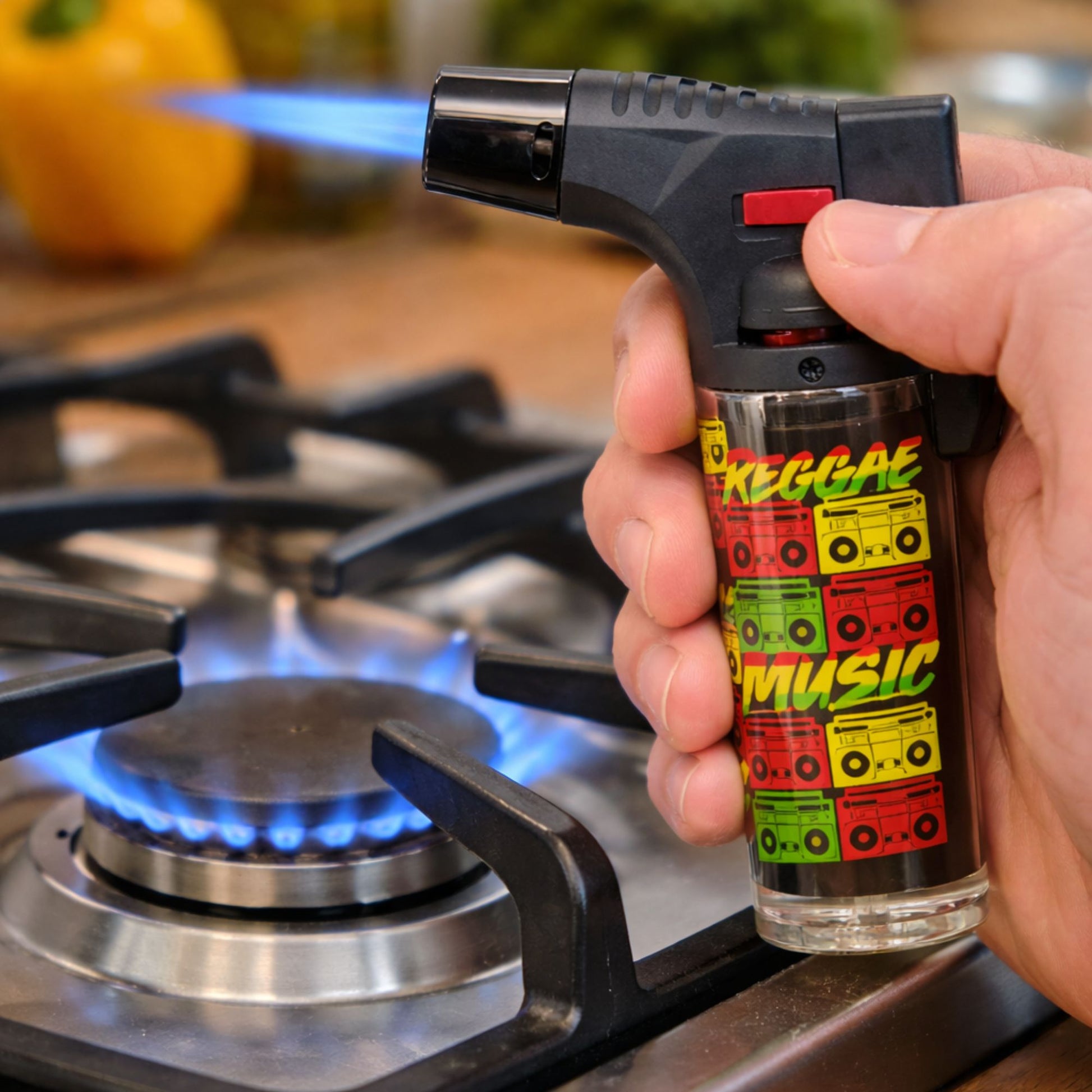 Hand holding a butane lighter with 'Reggae Music' design in front of a gas stove.