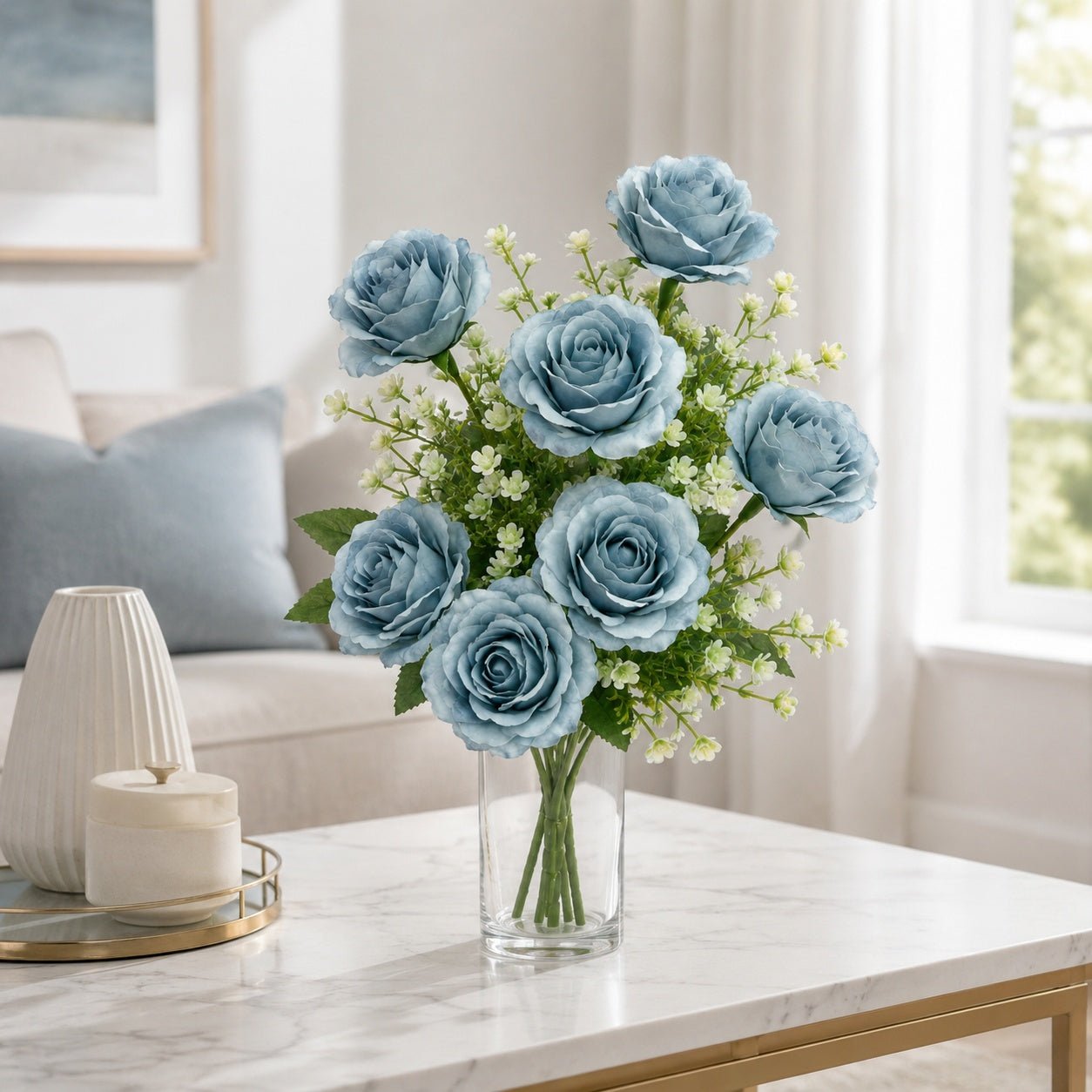 Bouquet of blue flowers in a clear vase on a marble table in a living room.
