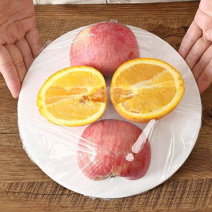 Apples and oranges on a plate with cling film being applied