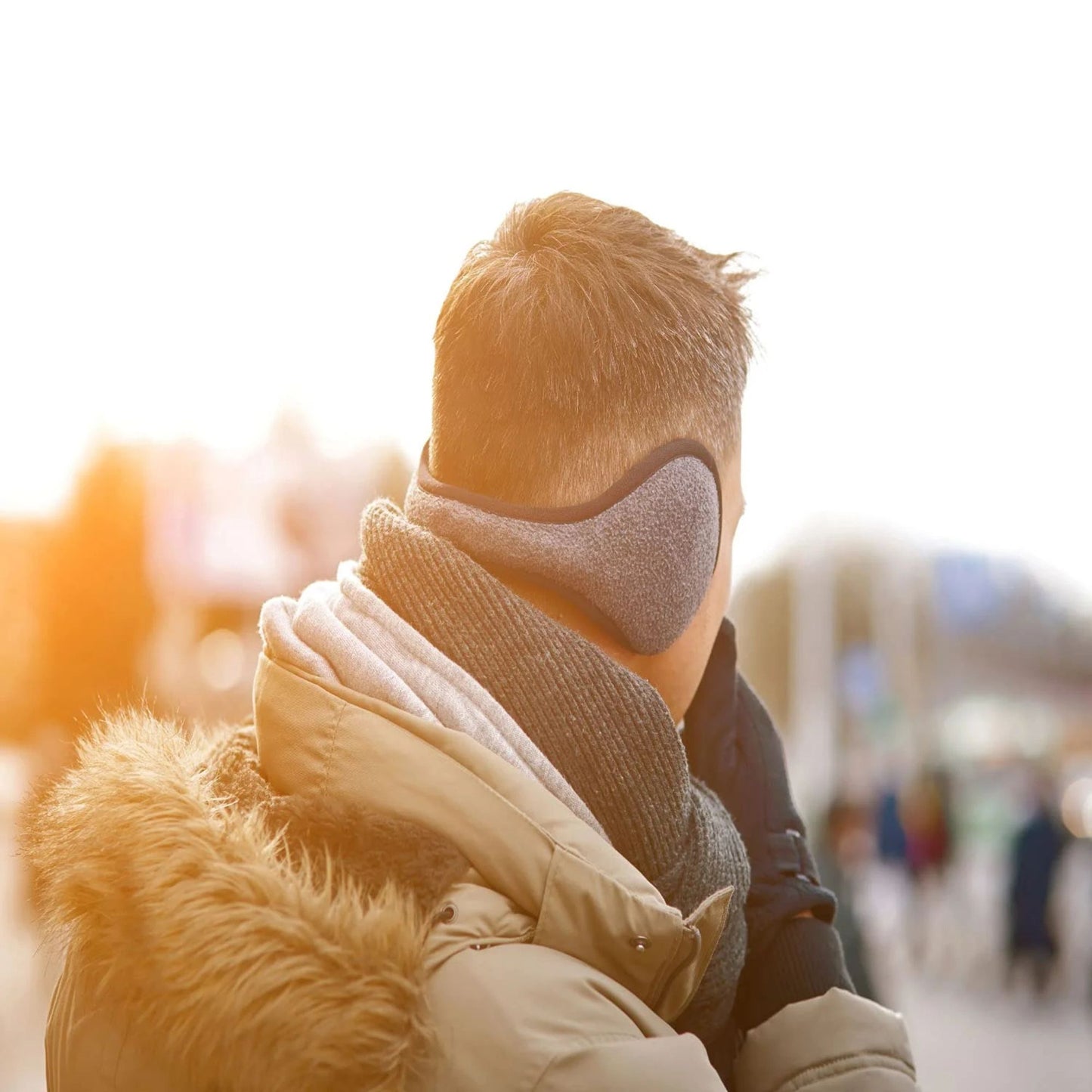 Person wearing a scarf and face mask in an urban setting with a blurred background