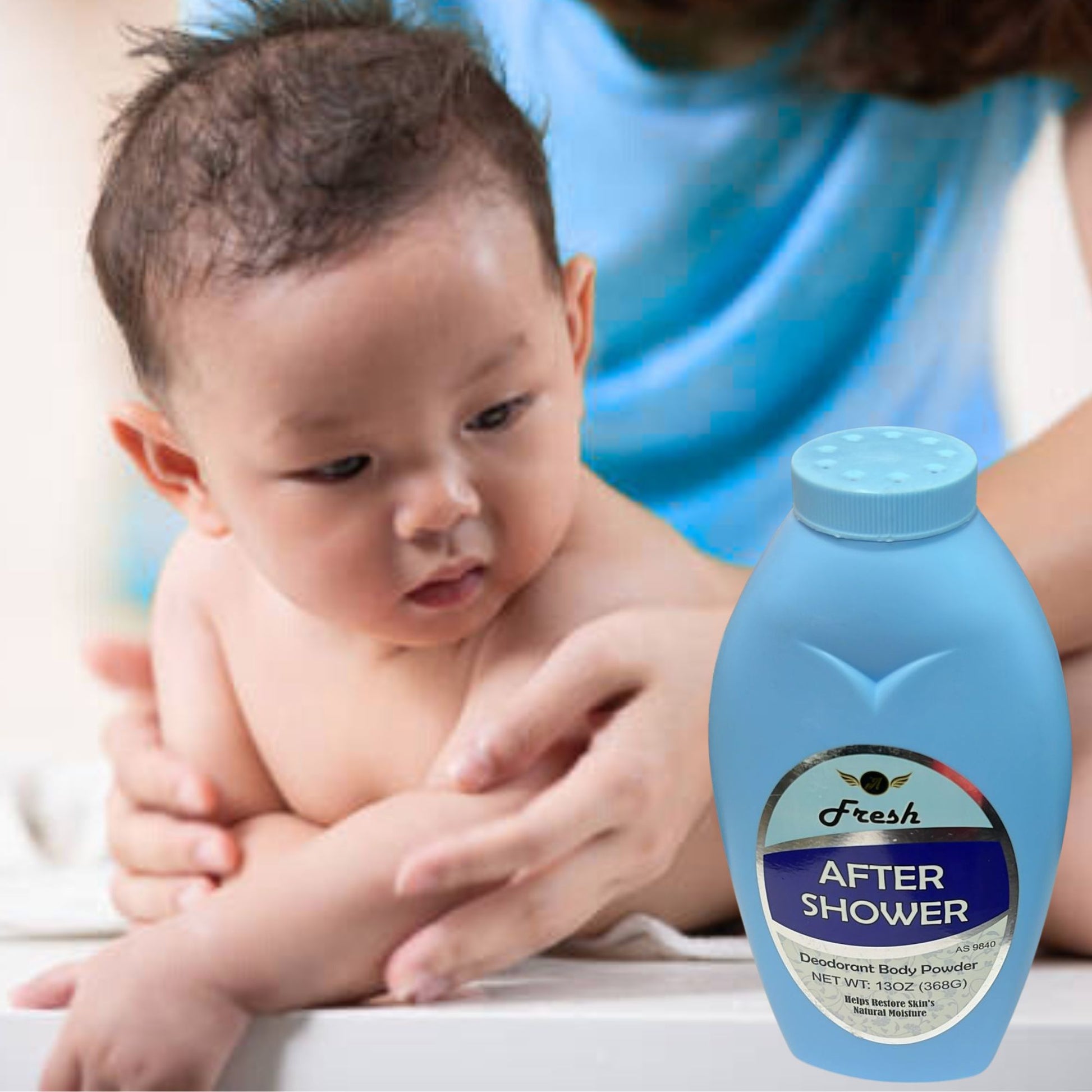 Baby being held by an adult with a bottle of 'Fresh' after shower product in the foreground.