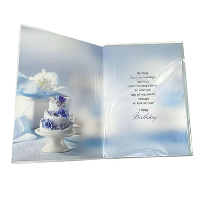 Open birthday card with a cake and flowers on one side and a birthday message on the other, on a white background.