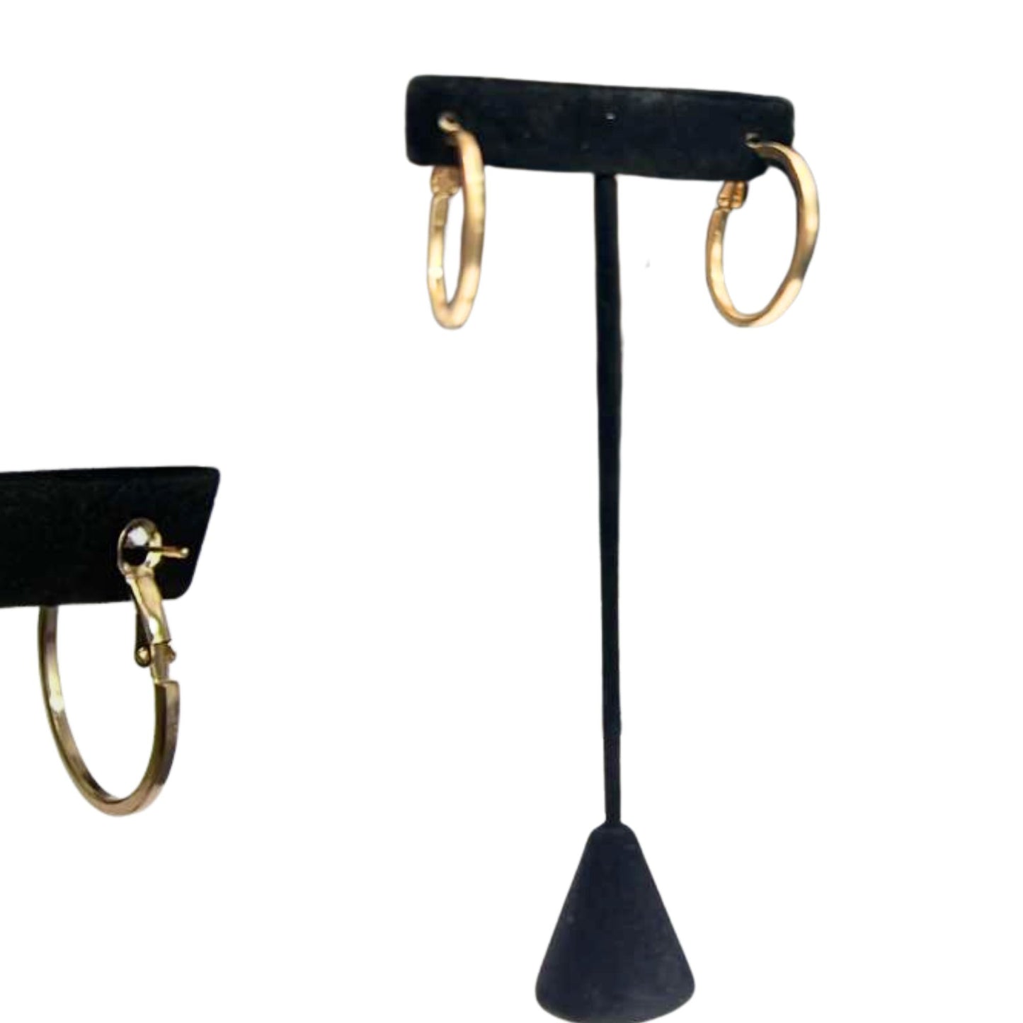 Gold hoop earrings on a black earring stand against a white background