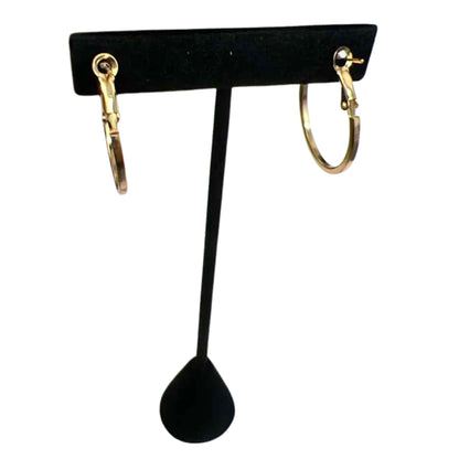 Gold hoop earrings on a black earring stand against a white background