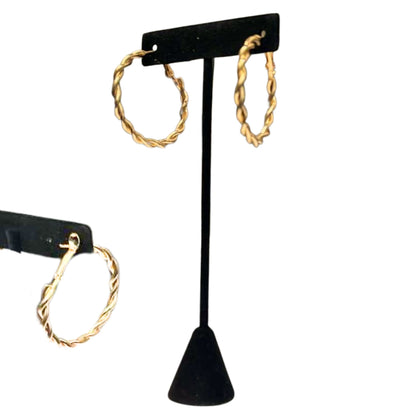 Gold hoop earrings on a black earring stand against a white background