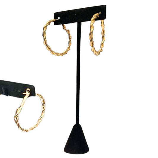 Gold hoop earrings on a black earring stand against a white background