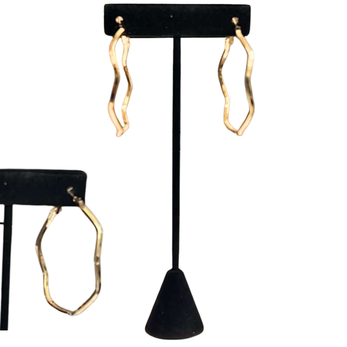 Gold hoop earrings on a black earring stand against a white background