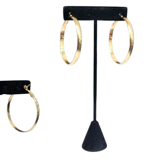 Gold hoop earrings on a black earring stand against a white background