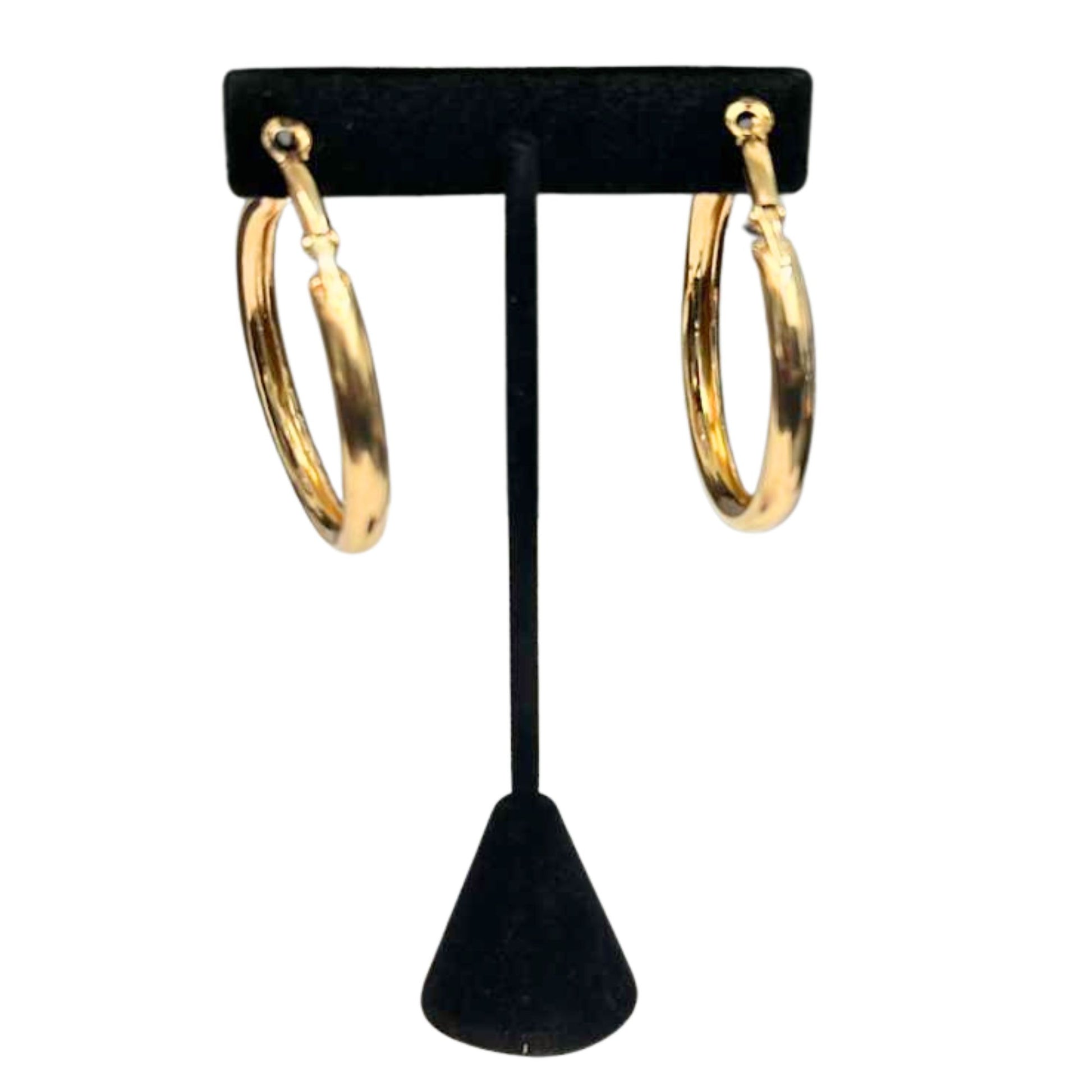 Gold hoop earrings on a black earring stand against a white background