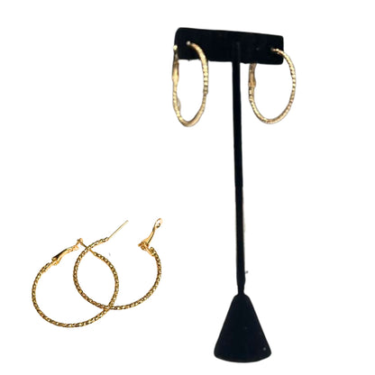 Gold hoop earrings on a black T-shaped stand with additional earrings on a white background