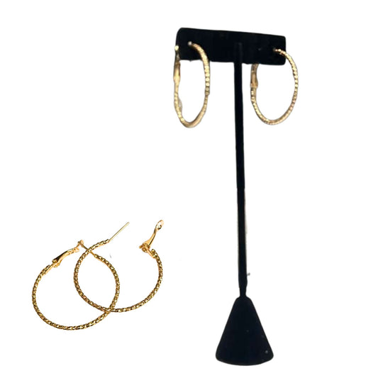 Gold hoop earrings on a black T-shaped stand with additional earrings on a white background