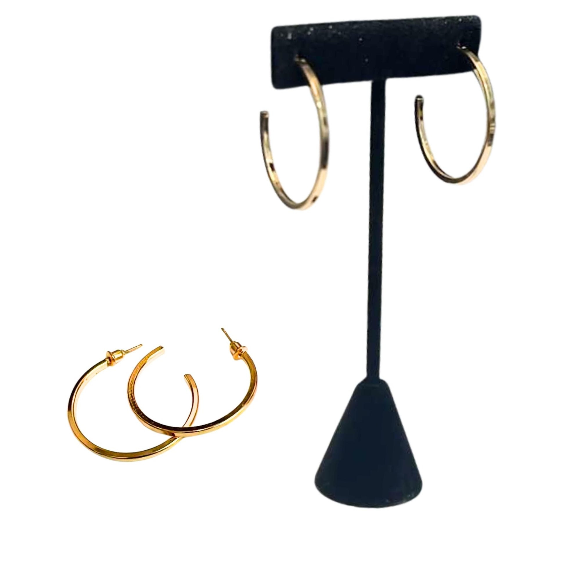 Gold hoop earrings on a black T-shaped earring stand against a white background