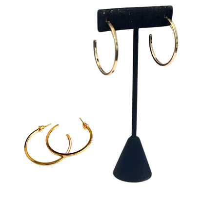 Gold hoop earrings on a black T-shaped earring stand against a white background
