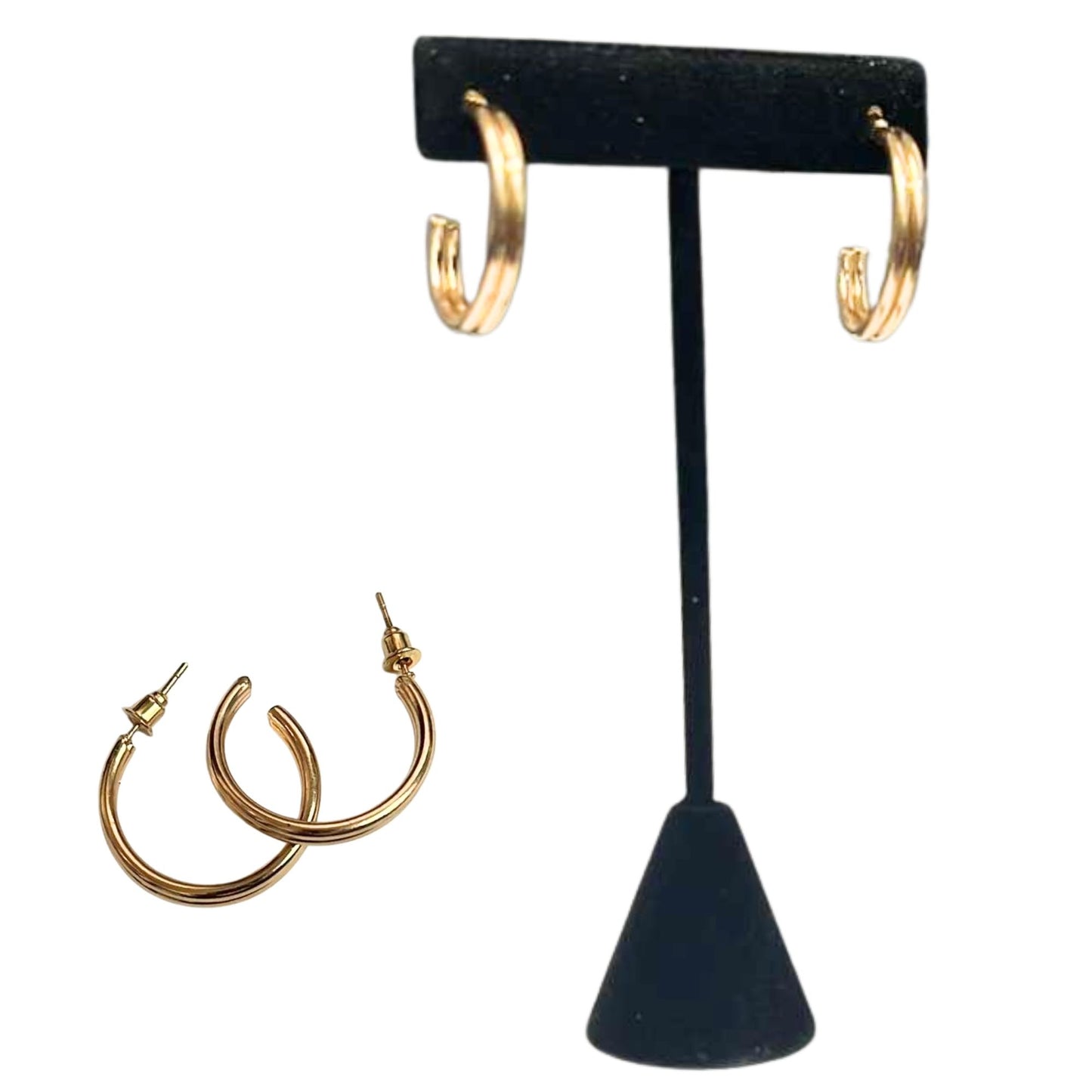 Gold hoop earrings on a black earring stand with additional earrings displayed below.