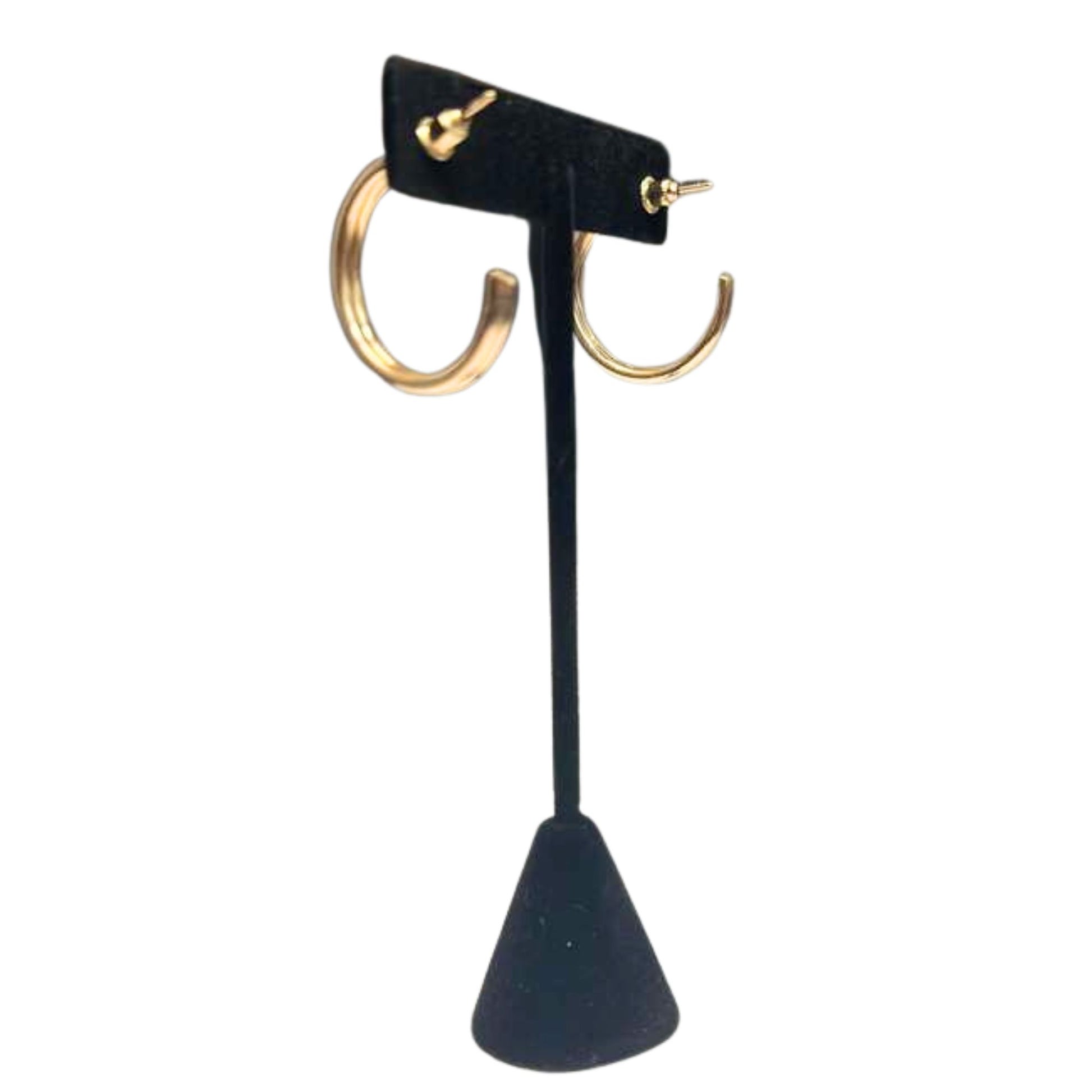 Gold hoop earrings on a black stand against a white background